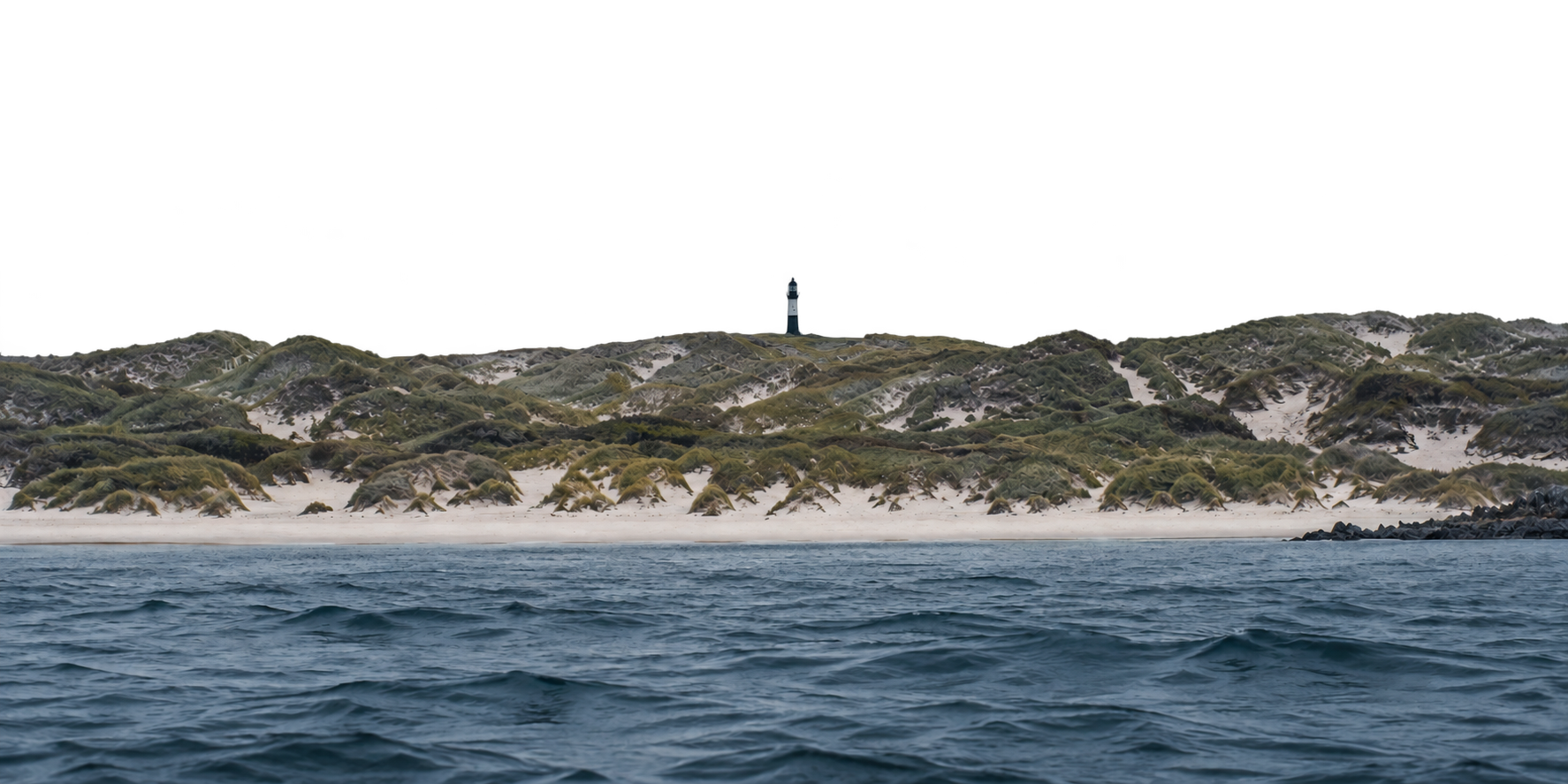 A distant striped lighthouse above coastal grass dunes, pale sand and a stormy sea.